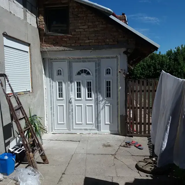 Bela PVC ulazna vrata sa bočnim prozorima na kući od cigle