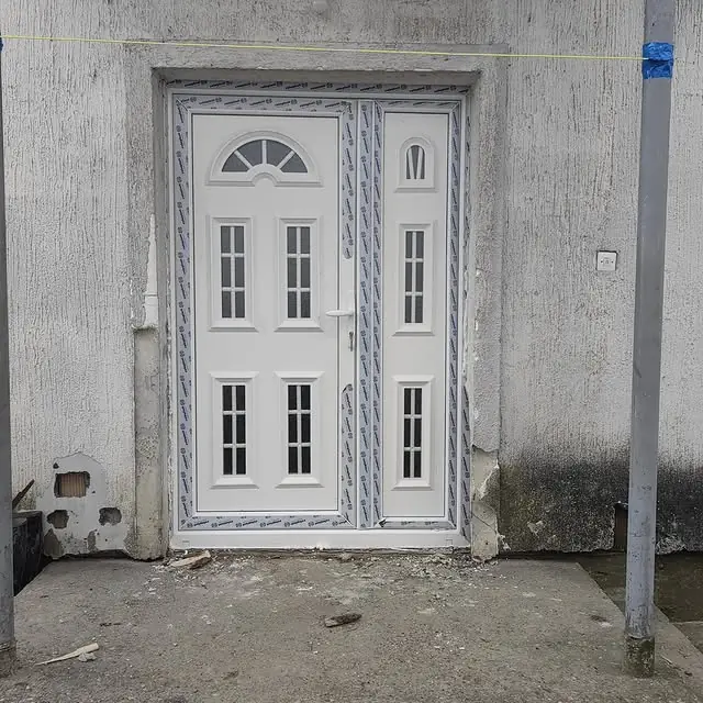 Bela PVC ulazna vrata sa bočnim prozorom, neposredno pre skidanja zaštitne folije